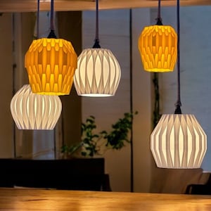 May include: Five hanging light fixtures with white and yellow pleated paper shades. The shades are all different sizes and shapes.