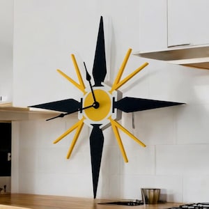 May include: A yellow and black starburst clock with black hands on a white wall.