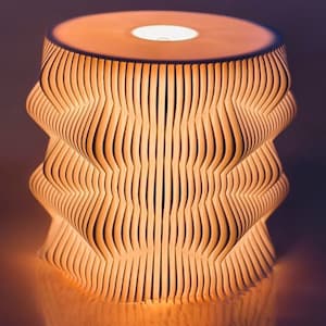 May include: A white, wooden lamp with a wavy, geometric design. The lamp is lit and casts a warm glow.