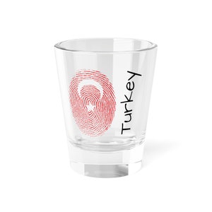 Könnte beinhalten: Ein klares Glas-Schnapsglas mit einem roten und weißen Fingerabdruck-Design und dem Wort "Türkei" auf der Seite.