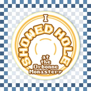 May include: A circular sticker featuring a yellow and white design with a pixelated font. The text reads I SHOWED HOLE at the Orbonne Monastery. The sticker is set against a blue and white checkered background, creating a distinct visual contrast.