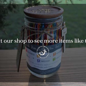May include: A glass jar with a wooden lid and a decorative tag. The jar contains colorful, color-coded items. The text on the jar reads "Seek Him Who You Are." The image also includes the text "Visit our shop to see more items like this."