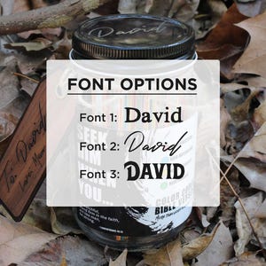May include: A clear glass jar with a black lid, showing font options for the name "David". The jar is set amongst fallen leaves. A wooden tag with the inscription "To: David, Love: Mom" is also visible.