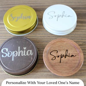 May include: Four personalized jar lids in gold, white, brown, and wood tones, each with the name "Sophia" engraved. The image includes the text "Personalize With Your Loved One's Name".