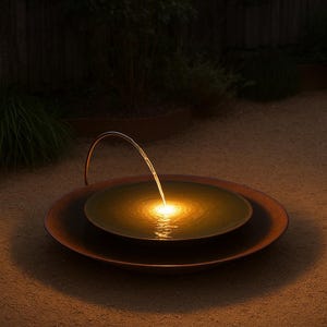 May include: A copper outdoor water fountain with a gentle stream of water flowing into a central basin. The water is illuminated by a warm, golden light, creating a tranquil ambiance. The fountain is set on a bed of sand.