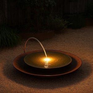 May include: Outdoor water fountain with a copper-colored basin. A curved metal spout arches over the water, creating a gentle stream. The water is illuminated by a warm, golden light, creating a tranquil ambiance in the garden.