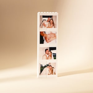 Puede incluir: Un bloque de fotos blanco con cuatro imágenes de una pareja. Las imágenes muestran a la pareja abrazándose y mostrando sus anillos de boda. El bloque está de pie sobre un fondo neutro.