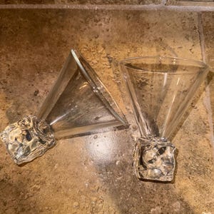 May include: Two clear glass martini glasses with a triangular base and a textured, clear glass bottom.