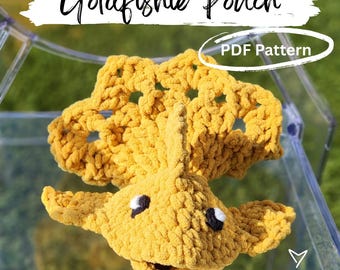 May include: A handmade, yellow crocheted goldfish pouch. The pouch features black and white eyes and a smiling mouth. The text "Goldfishie Pouch" is above the pouch, and "PDF Pattern" is in a white circle. The words "made by kym" are in the bottom right corner.