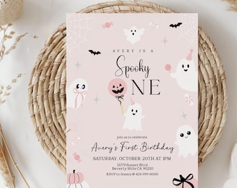 May include: A pink Halloween-themed invitation with the text "Avery is a Spooky One" and "Avery's First Birthday." The design includes cartoon ghosts, bats, and candy. The invitation is on a woven mat.