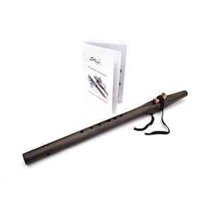 May include: A dark brown wooden Native American flute with six holes and a black leather strap. The flute comes with a booklet titled "Playing & Caring for your Native American Flute" and "Fundamentals of Basic Flutes".