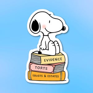 May include: A white Snoopy sticker sitting on a stack of books. The books are labeled "EVIDENCE", "TORTS", and "TRUSTS & ESTATES". The sticker has a light blue background.