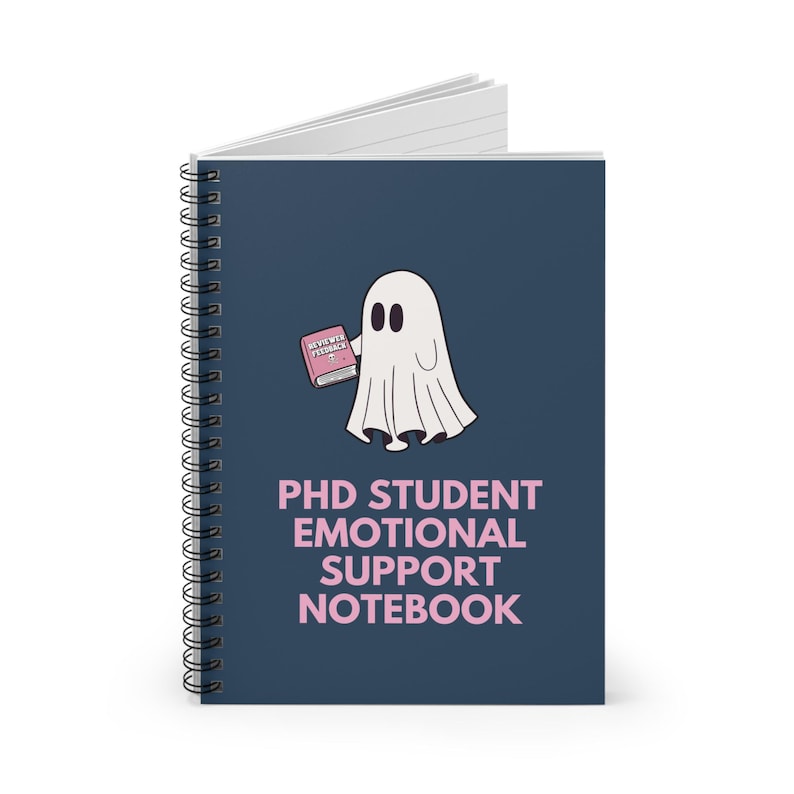K&ouml;nnte beinhalten: Ein dunkelblaues Spiralnotizbuch mit einem wei&szlig;en Geist, der ein rosa Buch mit der Aufschrift "REVIEW PEDAGOGY" h&auml;lt. Der Text auf dem Notizbuch lautet "PhD Student Emotional Support Notebook" in rosa.
