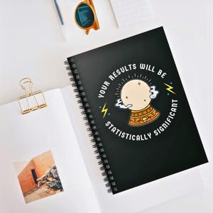 May include: Black spiral notebook with a white and yellow illustration of a crystal ball with the text "Your results will be statistically significant".