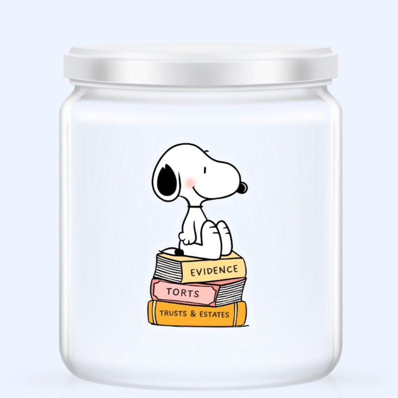 May include: A white glass jar with a white lid featuring a cartoon Snoopy character sitting on a stack of books. The books are labeled "Evidence", "Torts", and "Trusts & Estates". The jar has a light blue background.