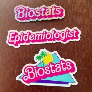 Pode incluir: Tr&ecirc;s adesivos rosa e branco com as palavras "Biostats" e "Epidemiologista" em uma fonte branca em negrito. O terceiro adesivo tem um design retr&ocirc; com uma palmeira e o sol e a palavra "Biostats" em uma fonte rosa.