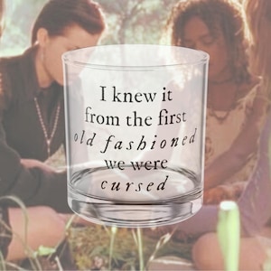 Puede incluir: Un vaso transparente con el texto "I knew it from the first old fashioned we were cursed" en escritura negra. El vaso es cilíndrico con una base gruesa. El fondo está borroso, mostrando personas.