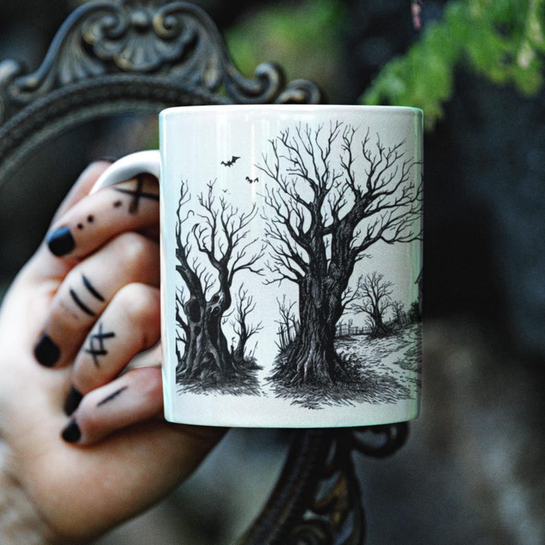 May include: White ceramic mug with a black and white illustration of two bare trees with branches reaching towards the sky. The trees are in a forest setting with a path leading through the trees.
