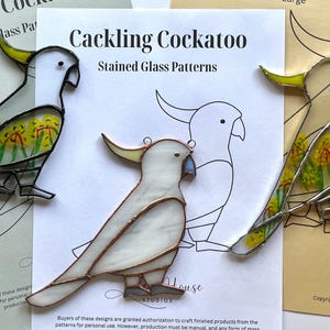May include: Three stained glass patterns of cockatoos. The patterns are on white paper with black outlines. The cockatoos are white with yellow accents and black eyes. The patterns are titled "Cackling Cockatoo Stained Glass Patterns".