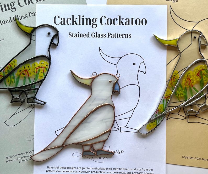 May include: Three stained glass patterns of cockatoos. The patterns are on white paper with black outlines. The cockatoos are white with yellow accents and black eyes. The patterns are titled "Cackling Cockatoo Stained Glass Patterns".