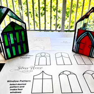 Może przedstawiać: Dwa domy z witraży, jeden zielony, a drugi czerwony, z arkuszem papieru przedstawiającym różne wzory okien. Papier zawiera tekst "Glass House Studios" i "Window Pattern Select desired pattern and make four windows".