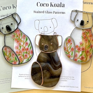 May include: Three stained glass koala bear ornaments. One is brown, another is clear with pink floral accents, and the third is white with pink floral accents. The text "Coco Koala Stained Glass Patterns" is visible.