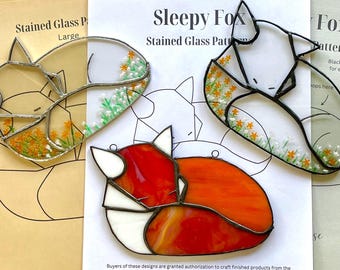 May include: Three stained glass patterns of sleeping foxes. The patterns are on white paper with the text "Sleepy Fox Stained Glass Pattern" at the top. The foxes are in different poses and colours, including orange, white, and black.