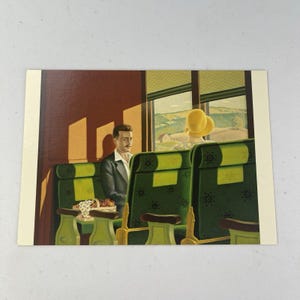 May include: Vintage postcard featuring a man in a suit and a woman in a yellow hat seated on a train. The interior of the train has green seats with floral patterns. The window shows a rural landscape with rolling hills and a farmhouse.