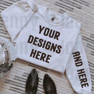 May include: White sweatshirt with the text "YOUR DESIGNS HERE" on the front and "AND HERE" on the sleeve. The sweatshirt is laying on a white and gray rug with a silver disco ball and a pair of black cowboy boots.