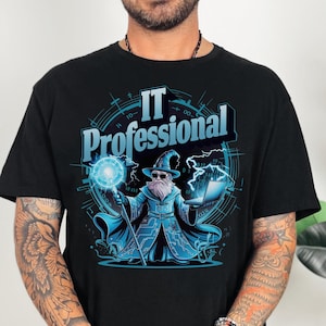May include: Black t-shirt with a graphic of a wizard holding a laptop and a magic wand. The wizard is wearing a blue robe with a circuit board pattern. The text "IT Professional" is written in a circle around the wizard.