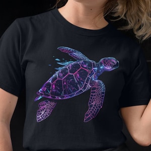 May include: A black t-shirt with a galaxy-style sea turtle graphic. The turtle is outlined in purple and blue with a white background.