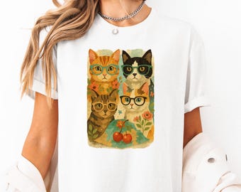 May include: White t-shirt with a graphic of four cats wearing glasses and surrounded by flowers and cherries.