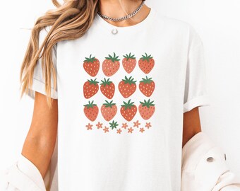 May include: White t-shirt featuring a graphic of red strawberries and pink flowers.