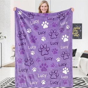 May include: Purple fleece blanket with a paw print pattern and the name "Lucy" repeated throughout.