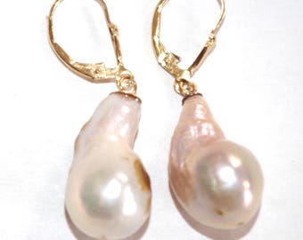 May include: A pair of gold-tone leverback earrings featuring large, irregularly shaped, off-white pearls with subtle pink and brown hues. The earrings have a classic, elegant design, suitable for special occasions.