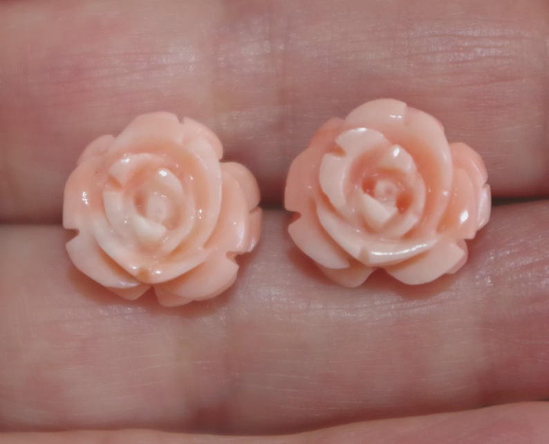 Puede incluir: Dos pendientes en forma de rosa rosa claro. Cada pendiente presenta p&eacute;talos detallados y un centro ligeramente m&aacute;s oscuro. Los pendientes son peque&ntilde;os y delicados, perfectos para a&ntilde;adir un toque floral a cualquier atuendo.