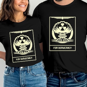 Puede incluir: Dos camisetas negras con un gráfico de una nube de hongo y el texto "Por la democracia".