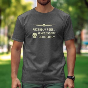 Puede incluir: Una camiseta gris oscuro jaspeada con una calavera pixelada y el texto "FRIENDLY FIRE... A NECESSARY DEMOCRACY".