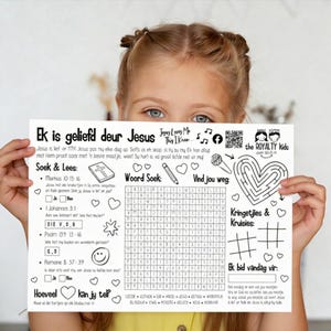 Könnte beinhalten: Ein weißes Aktivitätsblatt, das von einem Kind gehalten wird und Text und Illustrationen in Schwarz enthält. Das Blatt enthält ein Wortsuchrätsel, ein Labyrinth und Bibelverse. Der Text lautet "Ek is geliefd deur Jesus" und "Jesus Loves Me This I Know."