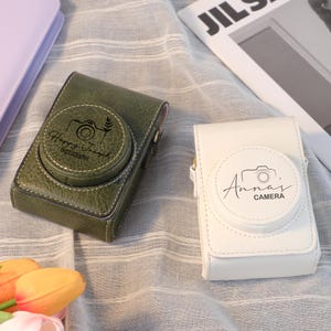 Könnte beinhalten: Ein Set aus drei Keramikbechern mit gesprenkelter, matter Oberfläche. Die Becher sind in Creme-, Hellgrau- und Dunkelgrautönen gehalten. Jeder Becher hat ein schlichtes, minimalistisches Design und einen abgerundeten Griff.