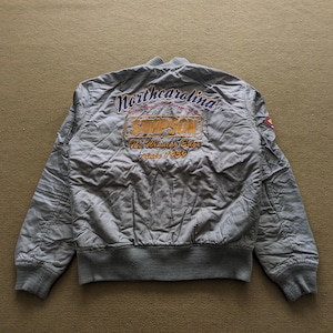 May include: A grey bomber jacket with "North Carolina" and "Simpson" embroidered on the back. The jacket has a ribbed collar, cuffs, and waistband.