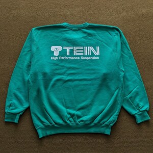 May include: A teal green sweatshirt with a white logo that reads "TEIN High Performance Suspension".