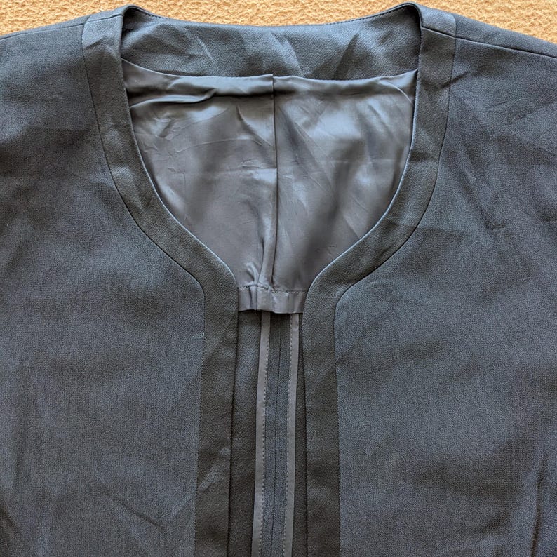 May include: A dark gray blazer with a deep V-neck and a center seam.