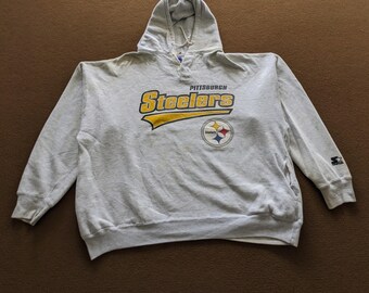 Puede incluir: Una sudadera con capucha gris con el logotipo de los Pittsburgh Steelers en amarillo y negro. El logotipo dice "Pittsburgh Steelers" y tiene una estrella amarilla con un contorno negro. La sudadera tiene un logotipo Starter negro y blanco en la manga derecha.