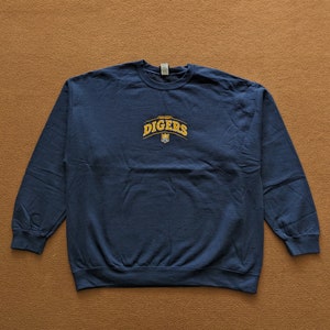 以下が含まれることがあります： 紺色のスウェットシャツに、金色の刺繍で「University of Utah Diggers」とロゴが入っています。