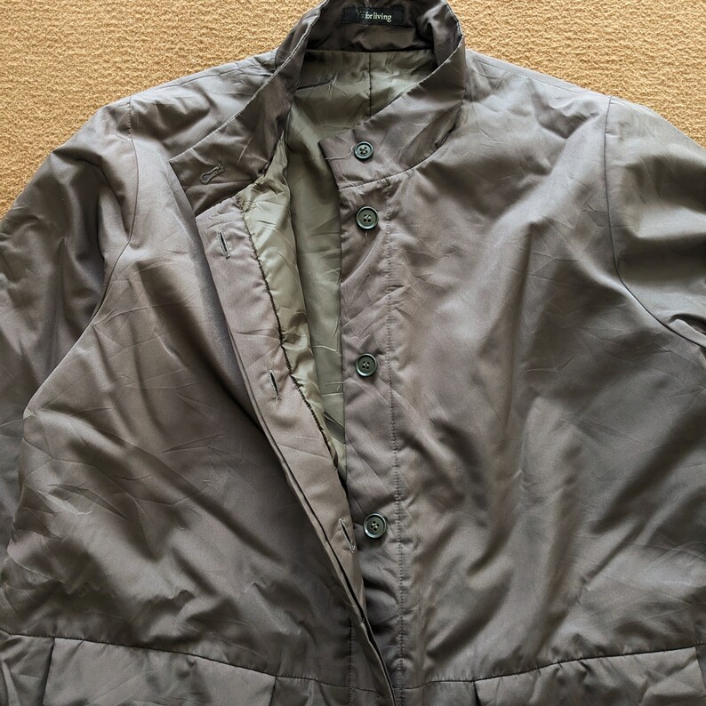 May include: A dark gray jacket with a stand-up collar and a zipper closure. The jacket has a buttoned placket and a single pocket on the left chest. The label on the jacket reads "Barling".