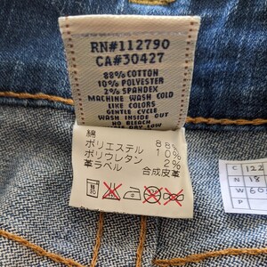 May include: A white care label with black text and symbols. The label includes the text "RN#112790 CA#30427 88% Cotton 10% Polyester 2% Spandex Machine Wash Cold Like Colors Gentle Cycle Wash Inside Out No Bleach Dry Low" and a Japanese language section with the text "綿 ポリエステル ポリウレタン 革ラベル 合成皮革 88% 10% 2%".