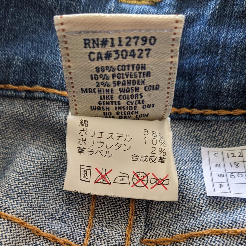May include: A white care label with black text and symbols. The label includes the text "RN#112790 CA#30427 88% Cotton 10% Polyester 2% Spandex Machine Wash Cold Like Colors Gentle Cycle Wash Inside Out No Bleach Dry Low" and a Japanese language section with the text "綿 ポリエステル ポリウレタン 革ラベル 合成皮革 88% 10% 2%".