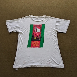 K&ouml;nnte beinhalten: Wei&szlig;es T-Shirt mit einem gr&uuml;nen und roten Aufdruck von Jack Skellington aus dem Film "Nightmare Before Christmas". Der Aufdruck zeigt den Filmtitel und eine Silhouette von Jack Skellington, der eine Tasche h&auml;lt.