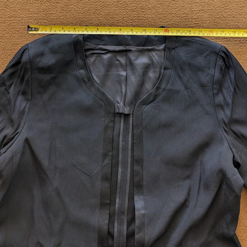 May include: A black blazer with a V-neck and a satin trim down the front.
